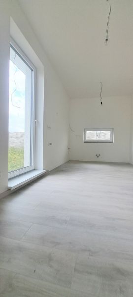 Innenraum eines Einfamilienhauses mit Holzboden und großem Fenster.