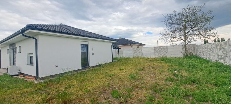 Ein Einfamilienhaus in Topoľnica mit weißer Fassade, Garten und Zaun.