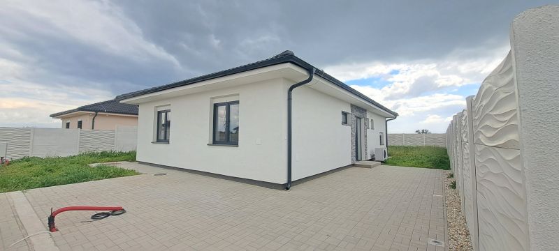 Ein Einfamilienhaus in Topoľnica mit weißer Fassade und gepflastertem Hof.