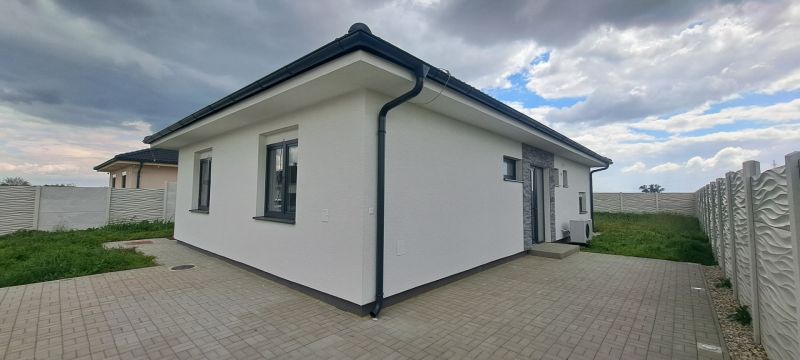 Ein Einfamilienhaus in Topoľnica mit weißer Fassade und gepflasterter Terrasse.