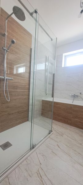 Ein Badezimmer mit einer modernen Dusche und einer Badewanne in einem Einfamilienhaus.