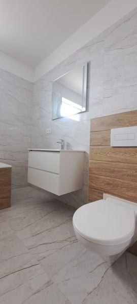 Badezimmer in einem Einfamilienhaus mit Waschbecken, Spiegel und Boden mit Holzdekor.