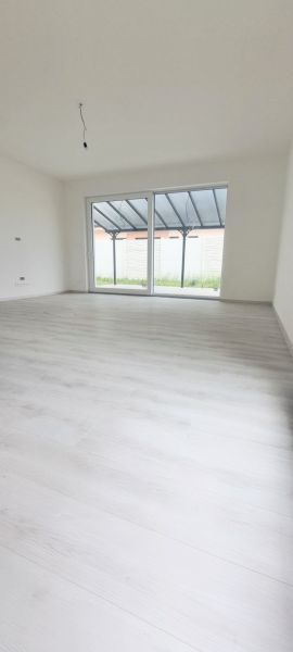 Innenraum eines Einfamilienhauses mit großem Fenster und Boden in Holzoptik.