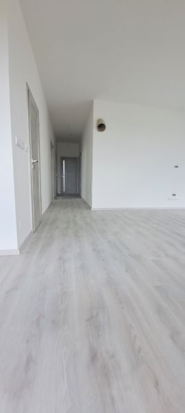 Innenraum eines Einfamilienhauses mit weißen Wänden und einem Boden in Holzoptik.