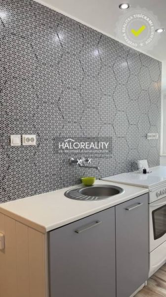 Küche mit gemusterten Fliesen und weißer Arbeitsplatte in einer 2-Zimmer-Wohnung.