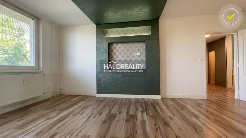 Wohnzimmer in einer Zweizimmerwohnung mit Holzboden und grüner Wand.