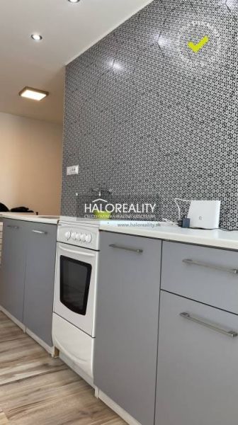 Küche in einer 2-Zimmer-Wohnung mit modernem Muster an der Wand und einem Boden in Holzoptik.