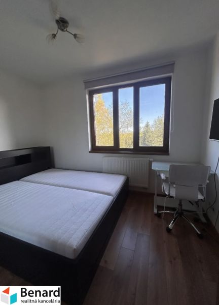 Schlafzimmer mit Bett, Tisch und Holzboden in einer 3-Zimmer-Wohnung.
