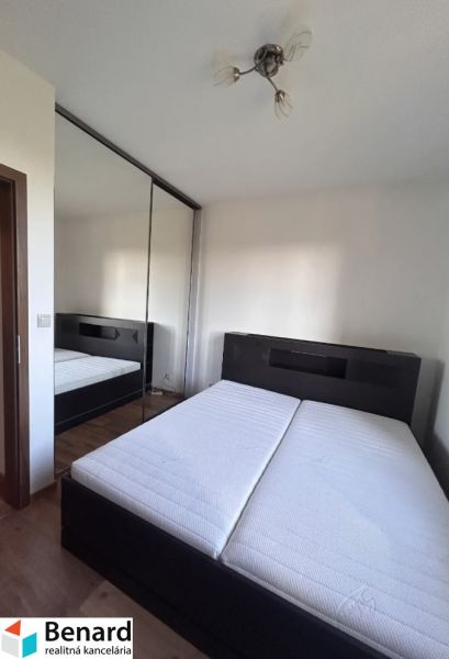 Schlafzimmer in einer 3-Zimmer-Wohnung mit einem Doppelbett, einem Spiegelschrank und einem Boden mit Holzdekor.