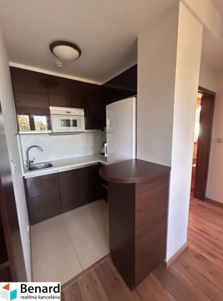 Küchenecke in einer 3-Zimmer-Wohnung mit Holzboden und dunklen Schränken.