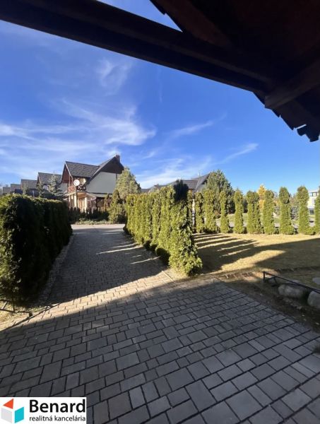 Luftaufnahme in Stará Lesná mit einer Zufahrtsstraße, umgeben von Grünflächen und Einfamilienhäusern.