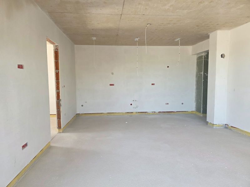 Ein Zimmer in einer 3-Zimmer-Wohnung mit Betondecke und nackten Wänden.