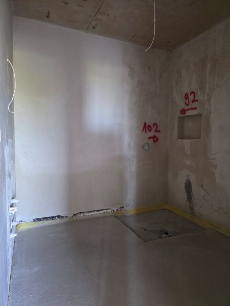 Innenraum einer 3-Zimmer-Wohnung mit verputzten Wänden und markierten Stellen für Installationen.