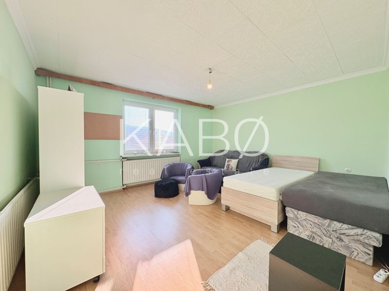 Ein Zimmer mit Betten, einem Sofa und einem Boden mit Holzdekor in einem Einfamilienhaus.