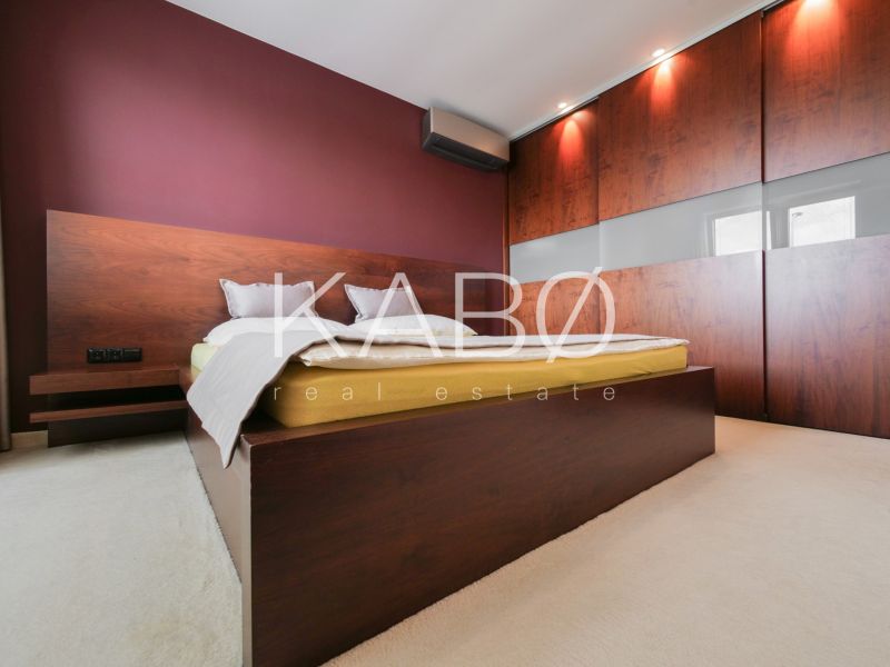 Schlafzimmer im Einfamilienhaus mit Bett, Einbauschrank und weinroter Wand.