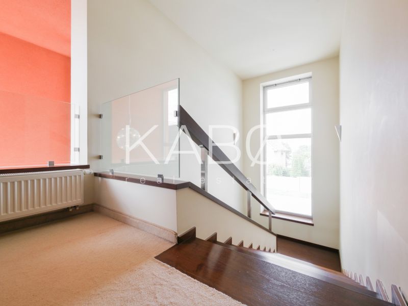 Eine Treppe mit modernem Geländer und Teppich in einem Einfamilienhaus, sonniger Raum.