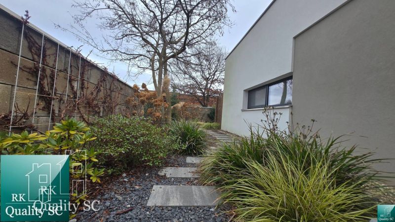Ein Einfamilienhaus in Senec mit einem gepflegten Gartenweg, verziert mit Kieselsteinen und grünen Pflanzen.