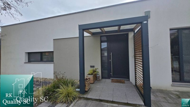 Einfamilienhaus in Senec mit minimalistischer Fassade, Eingangstüren und Pergola.