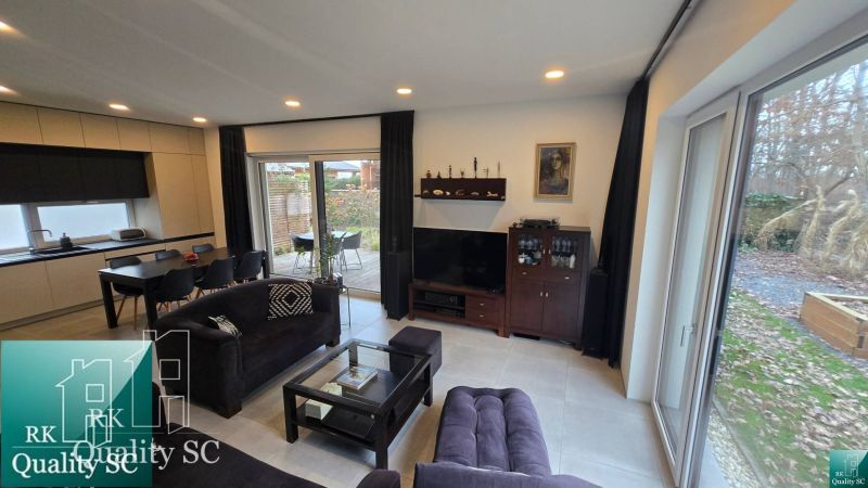 Wohnzimmer in einem Einfamilienhaus mit Sofa, Esstisch und Blick auf die Terrasse.