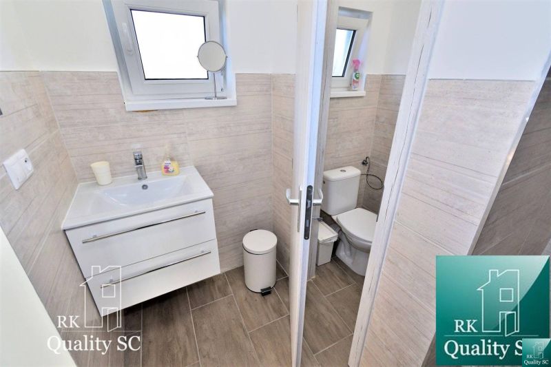 Badezimmer mit Waschbecken und Toilette in einem Einfamilienhaus, Boden mit Holzdekor.