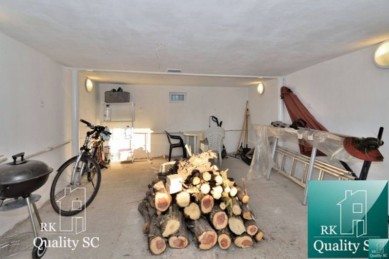 Keller eines Einfamilienhauses mit Fahrrad, Gartenmöbeln und gelagertem Brennholz.