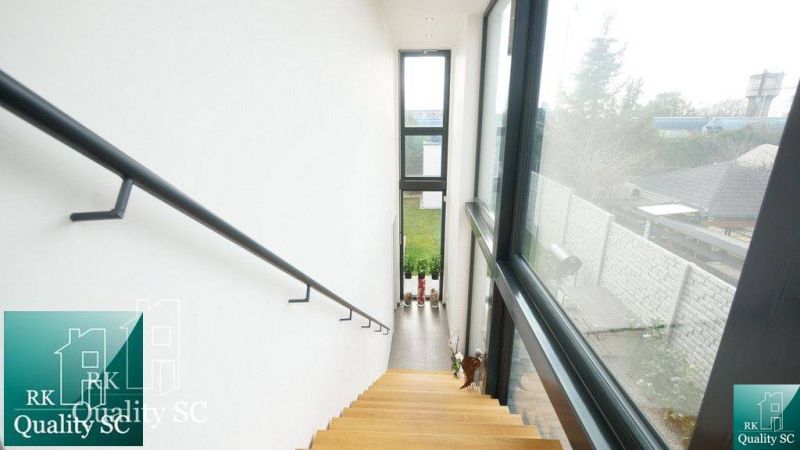 Treppe mit Holzdekor in einem Einfamilienhaus mit großen Fenstern und Blick in den Garten.