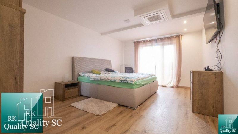 Schlafzimmer mit Bett, Kommode, Nachttischen und Holzboden in einem Einfamilienhaus.
