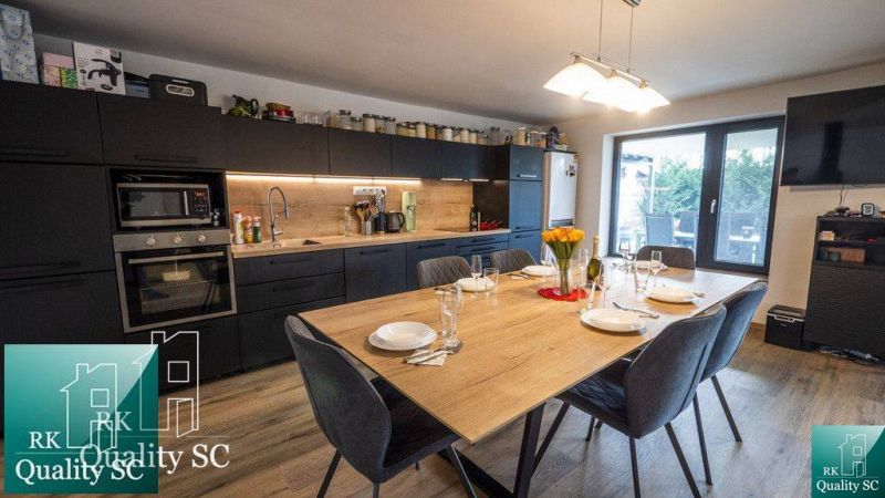 Küche im Einfamilienhaus mit großem Esstisch und Boden in Holzoptik.