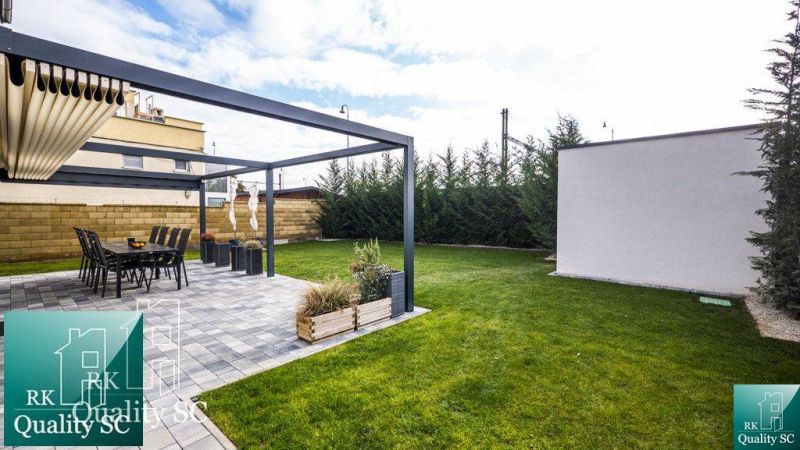 Der Garten eines Einfamilienhauses an den Sonnenseen Süd in Senec mit Terrasse und Rasen.