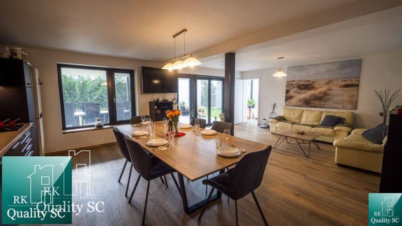 Wohnzimmer mit Holzboden in einem Einfamilienhaus, eingerichtet mit Esstisch und Sofa.