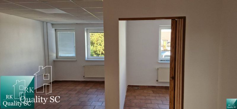 Innenraum eines Einfamilienhauses mit Terrakottaboden, weißen Wänden und Heizkörpern unter den Fenstern.