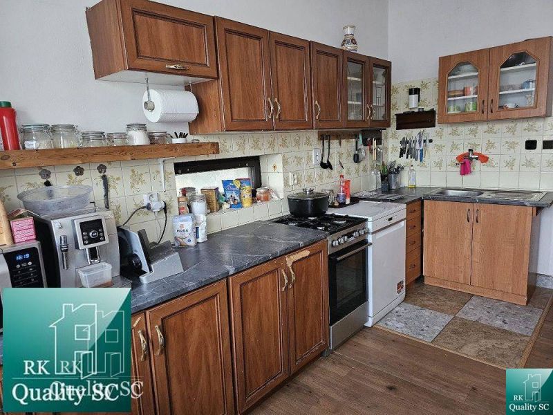 Eine Küche in einem Einfamilienhaus mit Holzschränken und einem Boden mit Holzdekor.