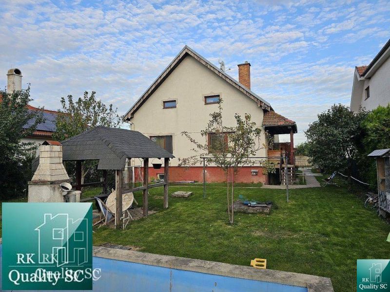 Ein Einfamilienhaus in Turany mit Rasen, Pavillon und einem Außenkamin im Garten.