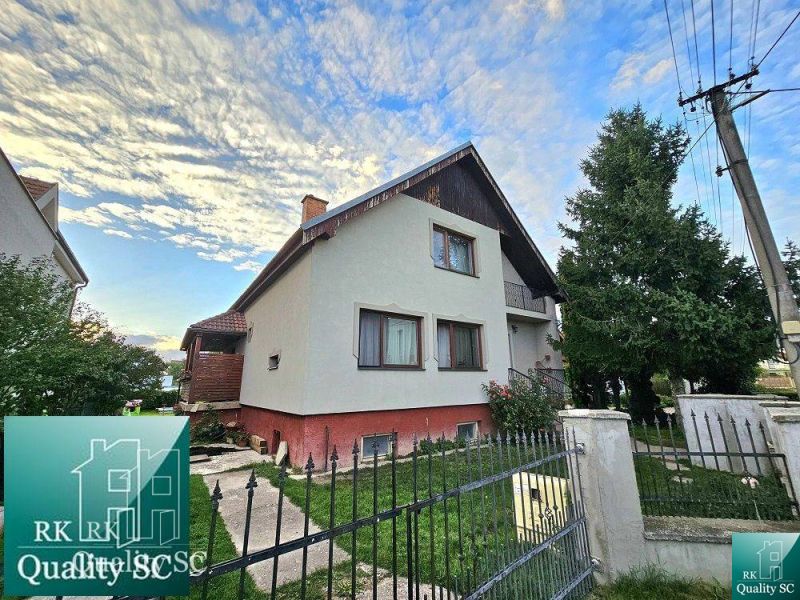 Ein Einfamilienhaus in der Straße in Turna mit einem eingezäunten Grundstück und Bäumen im Garten.