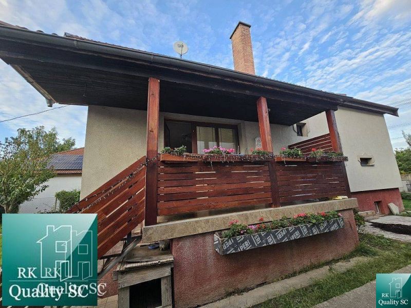 Ein Einfamilienhaus in der Gemeinde Tureň mit einem Holzgeländer und Blumendekoration auf der Veranda.