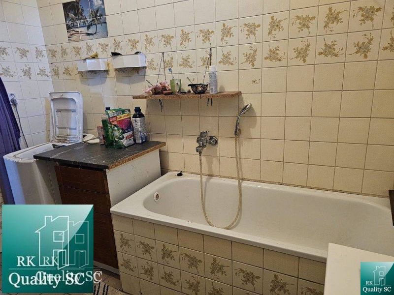 Ein Badezimmer mit Badewanne in einem Einfamilienhaus, gefliest mit Blumenmuster.