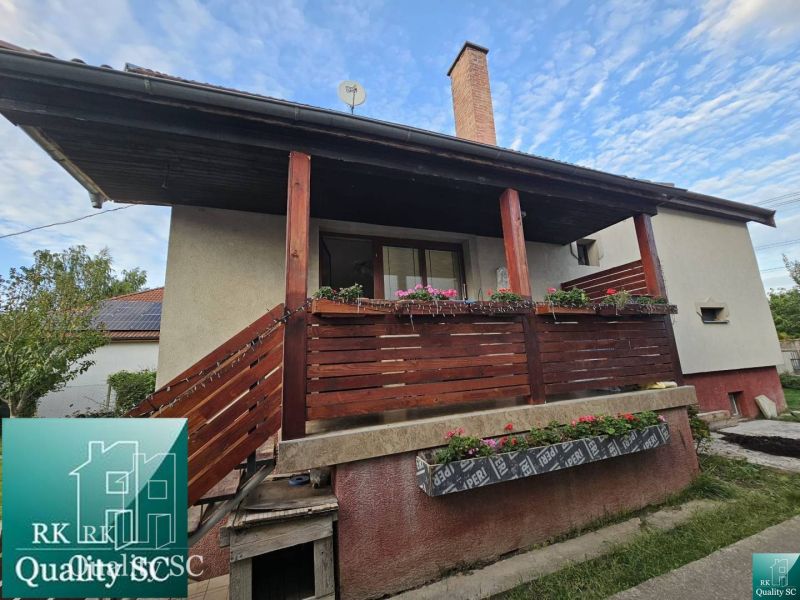 Das Einfamilienhaus in der Straße in Turna hat einen Holzbalkon mit Blumenschmuck.