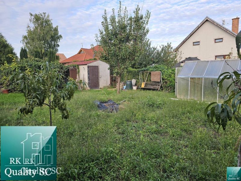 Garten eines Einfamilienhauses in der Gemeinde Tureň mit Rasen, Gewächshaus und Bäumen.