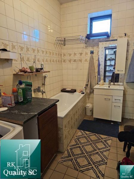Badezimmer im Einfamilienhaus mit Badewanne, Schrank und Fliesen an den Wänden.