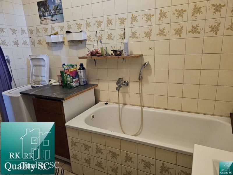 Badezimmer eines Einfamilienhauses mit Badewanne und Waschmaschine, dekorative Fliesen mit Blumen.