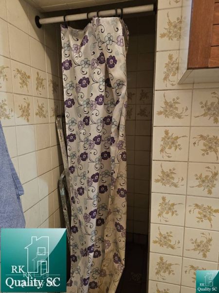 Duschkabine mit Blumen-Duschvorhang und Fliesen im Einfamilienhaus.