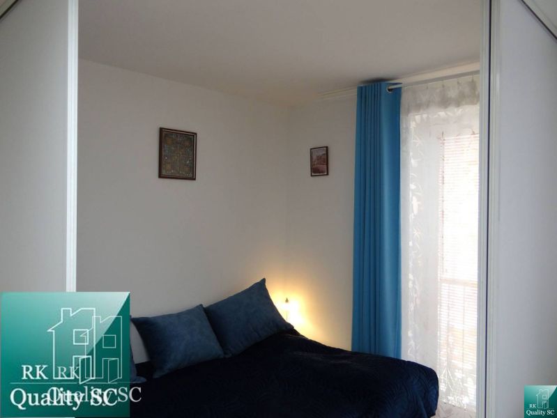 Schlafzimmer in einer Einzimmerwohnung mit blauen Vorhängen und einfacher Dekoration.