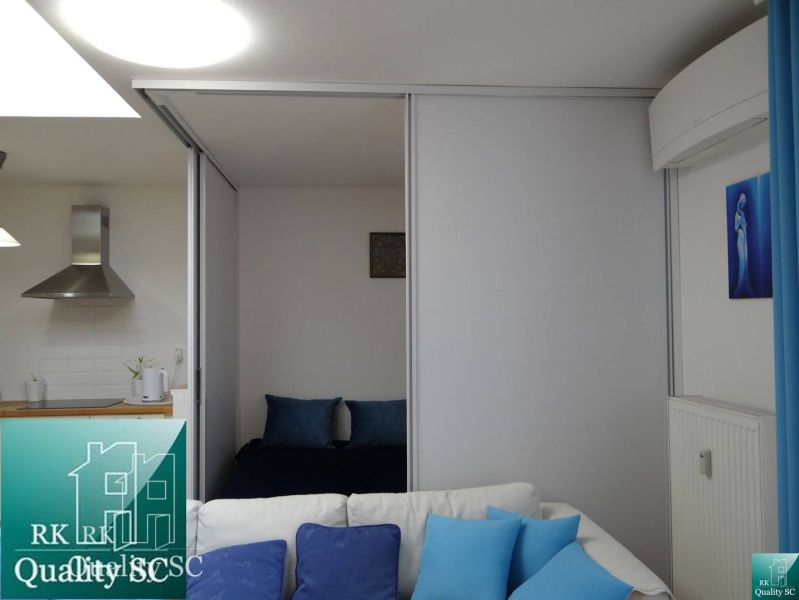 Wohnbereich in einer Einzimmerwohnung mit Kochnische und blauen Accessoires.
