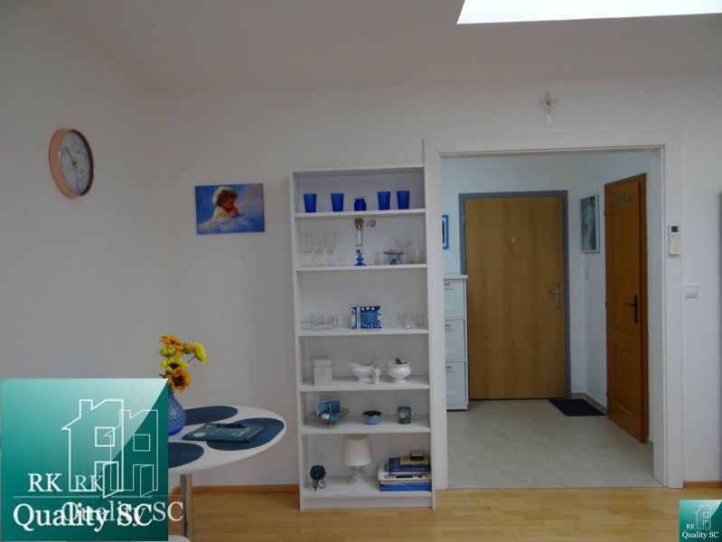 Innenraum einer Einzimmerwohnung mit Holzboden, weißen Möbeln und Dekorationen.