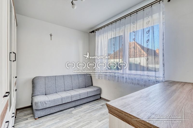 Ein Sofa und Schränke im Zimmer eines Einfamilienhauses, mit einem Boden in Holzoptik.