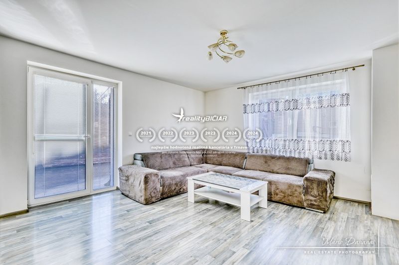 Wohnzimmer in einem Einfamilienhaus mit Sofa und Tisch, Boden mit Holzdekor.