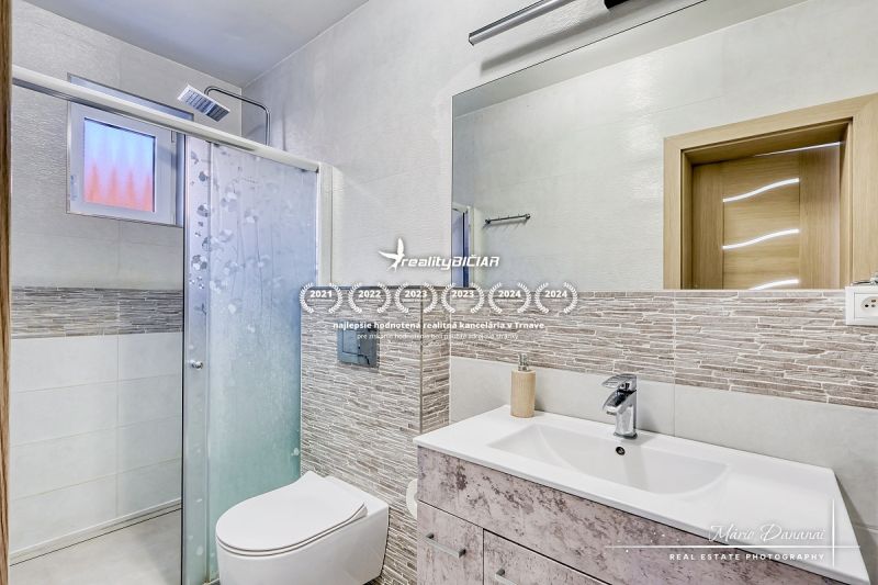 Kompaktes Badezimmer mit Toilette und Dusche in einem Einfamilienhaus, dekoriert mit Mosaikfliesen.