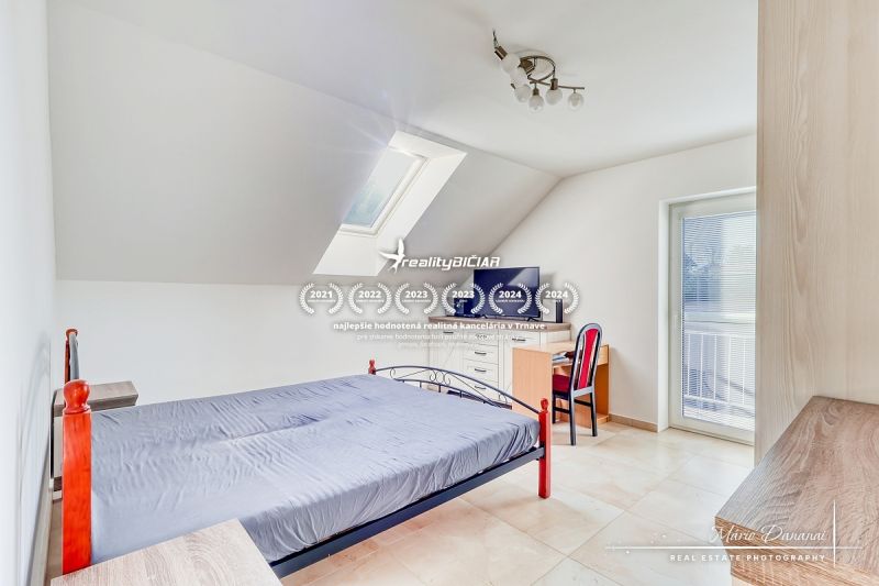 Ein Schlafzimmer im Dachgeschoss eines Einfamilienhauses mit einfacher Einrichtung und Dachfenster.