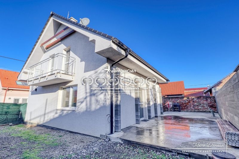 Ein Einfamilienhaus in Hrnčiarovce nad Parnou mit einer Betonterrasse und einem Balkon im Obergeschoss.