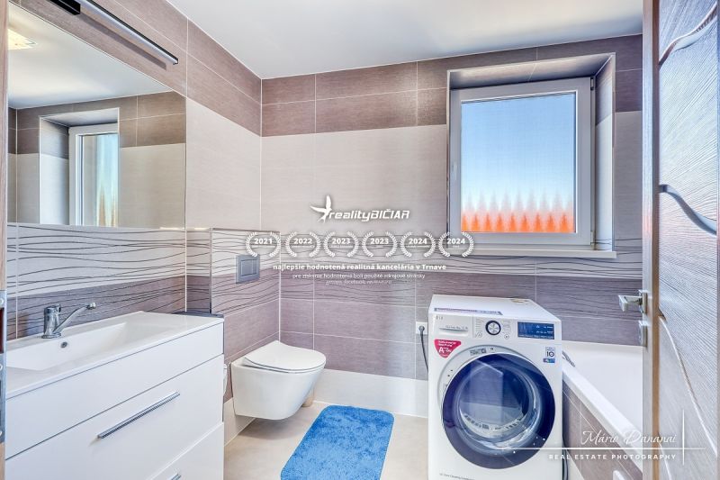 Badezimmer in einem Einfamilienhaus mit Waschmaschine, Waschbecken und Fenster mit Mattglas.